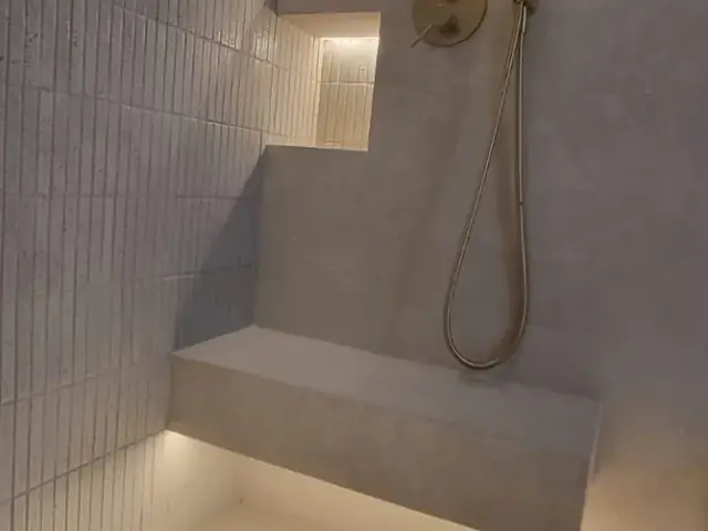 Finished shower with brass fixtures and floating tile niches