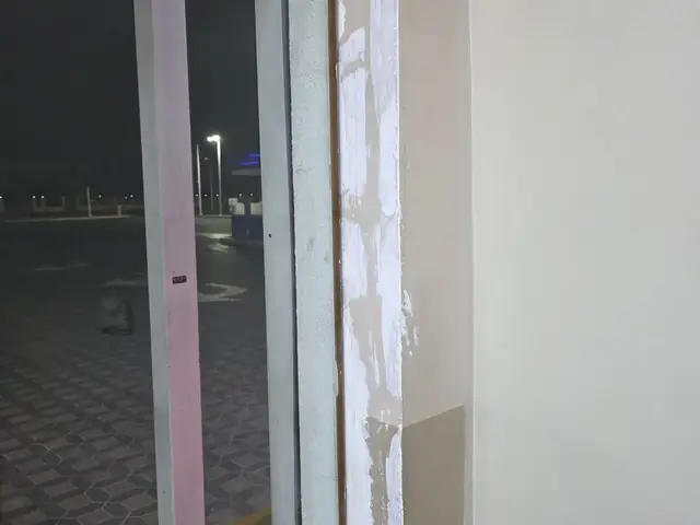 Technician painting ceiling corner at café fit-out