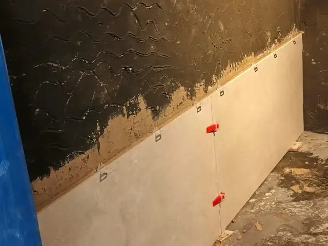 Bathroom wall tiling in progress over waterproofing membrane