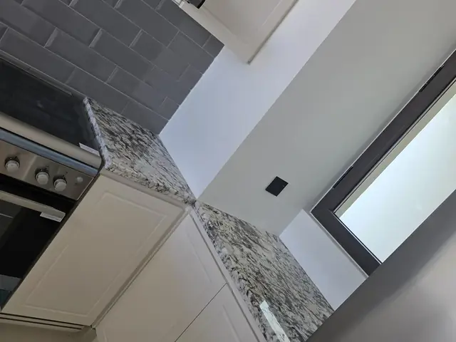 Kitchen cabinetry with granite countertop and extractor hood