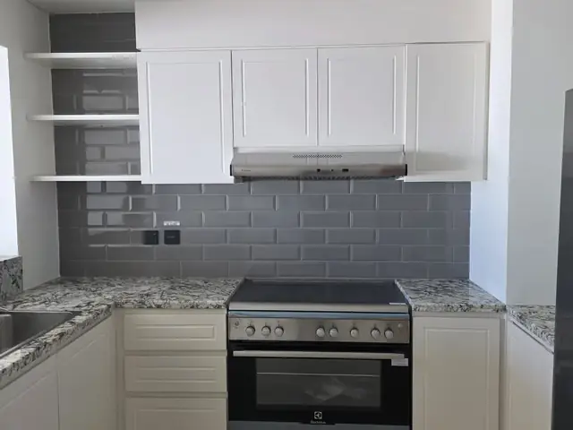 Completed kitchen with grey subway tile splashback and granite counters