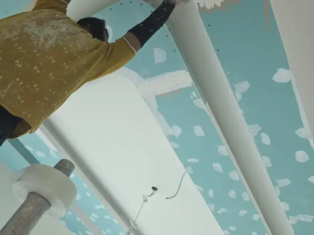 Technician finishing curved gypsum ceiling detail