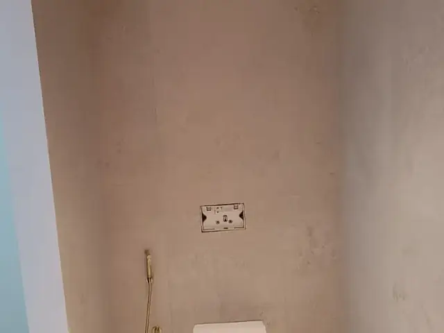 Finished minimalist toilet room with stone-look wall tiling
