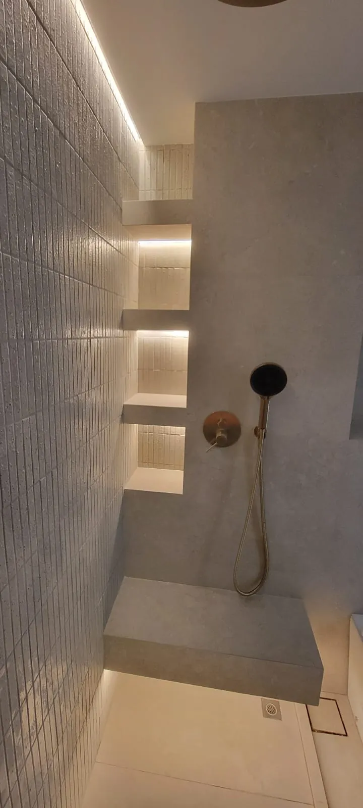 Walk-in shower with brass fixtures and tiled display niches