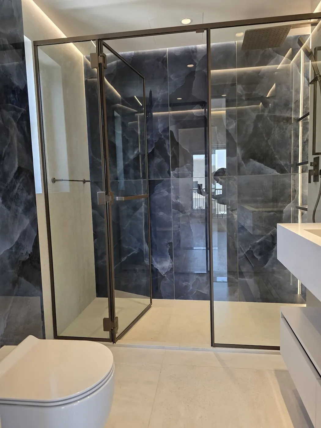 Walk-in glass shower with onyx marble walls