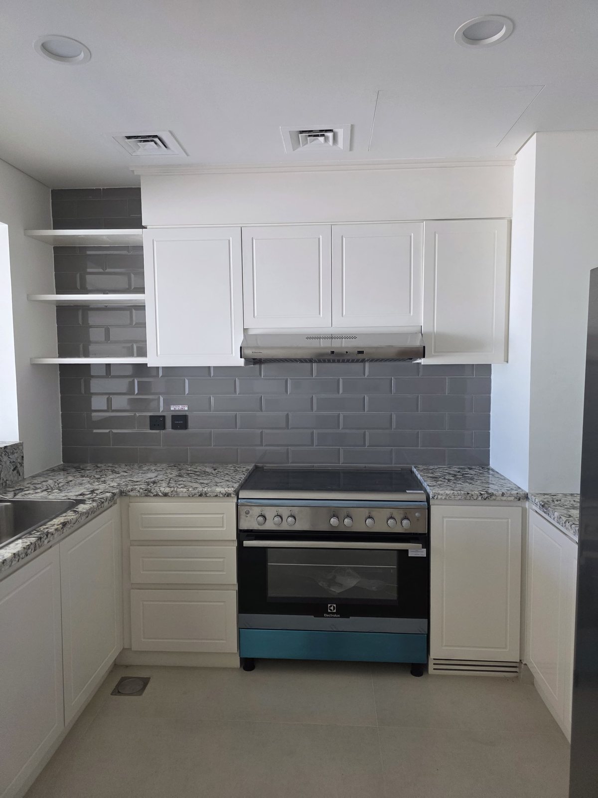 Completed kitchen with grey subway tile splashback and granite counters