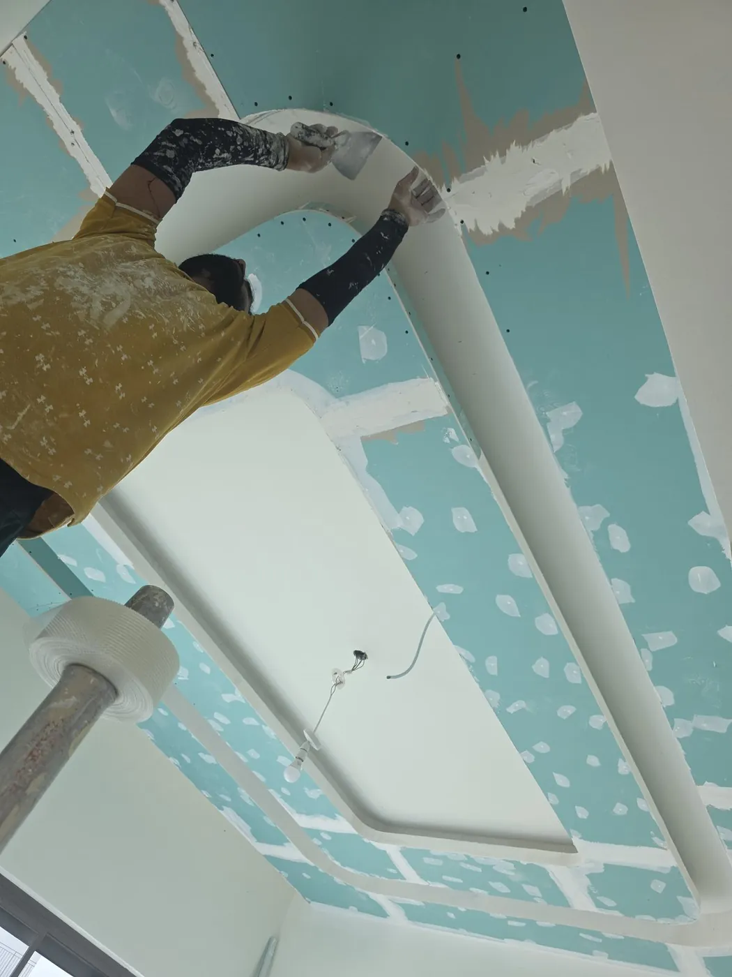 Technician finishing curved gypsum ceiling detail
