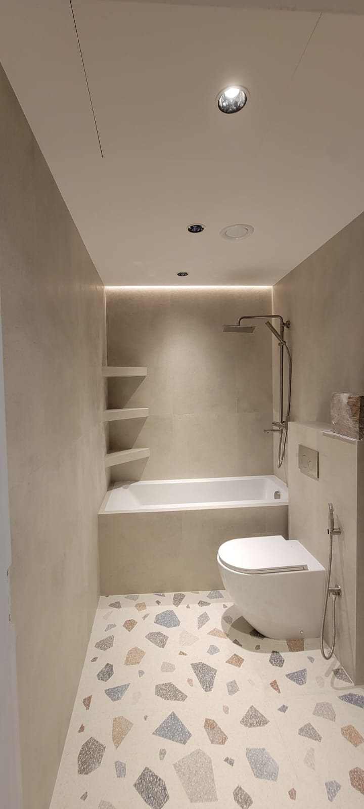 Bathtub bathroom with terrazzo flooring and built-in shelving