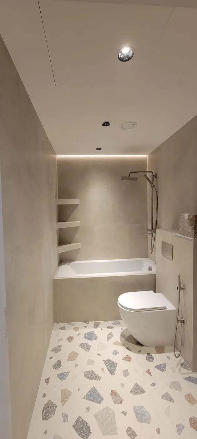 Bathtub bathroom with terrazzo flooring and built-in shelving